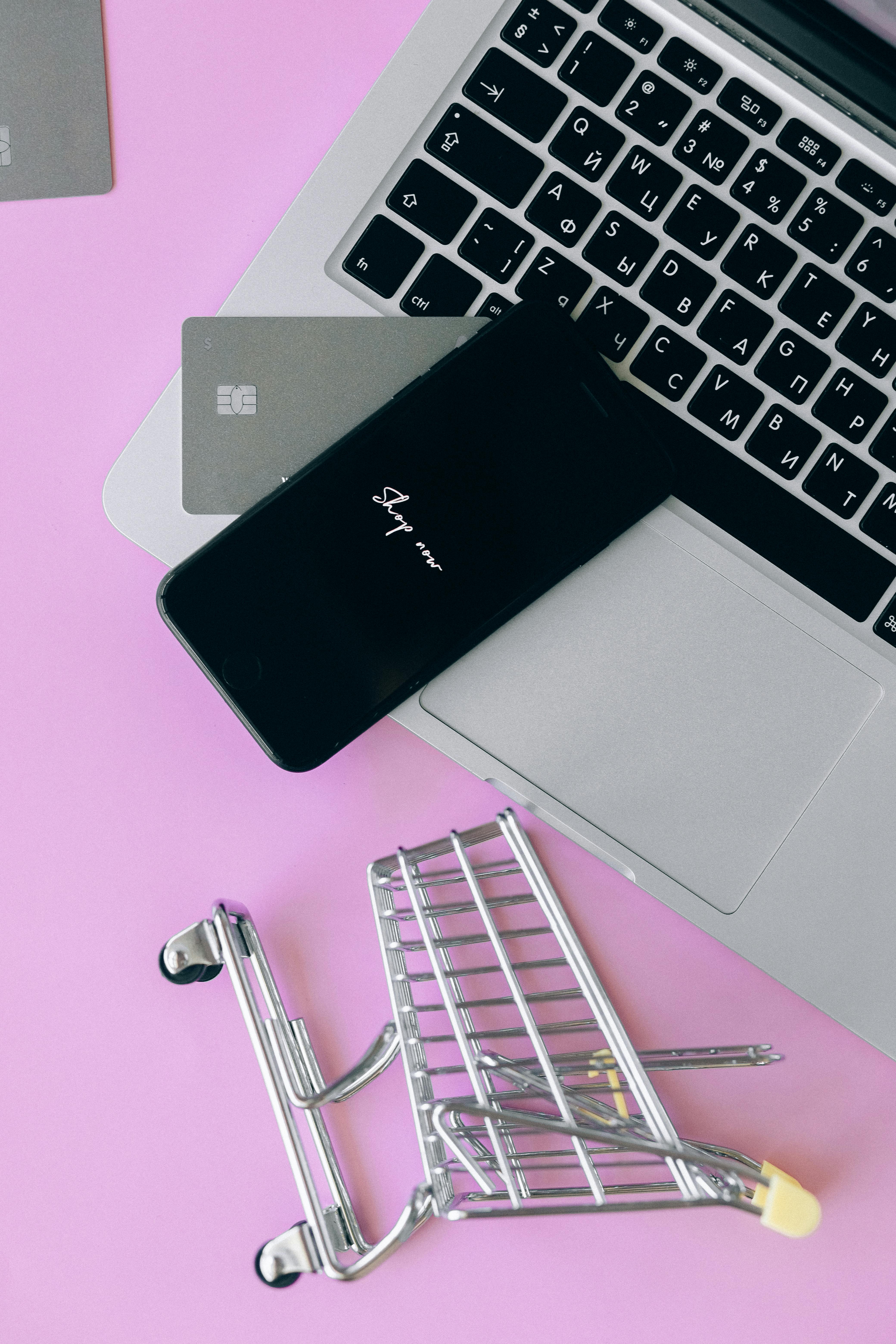 Laptop with smartphone and shopping cart, symbolizing online shopping and ecommerce.